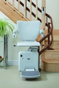 Λευκό αναβατόριο καρέκλα σε καμπυλωτή ράγα, τοποθετημένο σε ξύλινη σκάλα εσωτερικού χώρου.