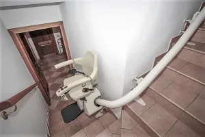 Αναβατόριο καρέκλα σκάλας παρκαρισμένο σε πλατύσκαλο, φωτογραφημένο από ψηλά. Η ράγα ακολουθεί τη γωνία της σκάλας.